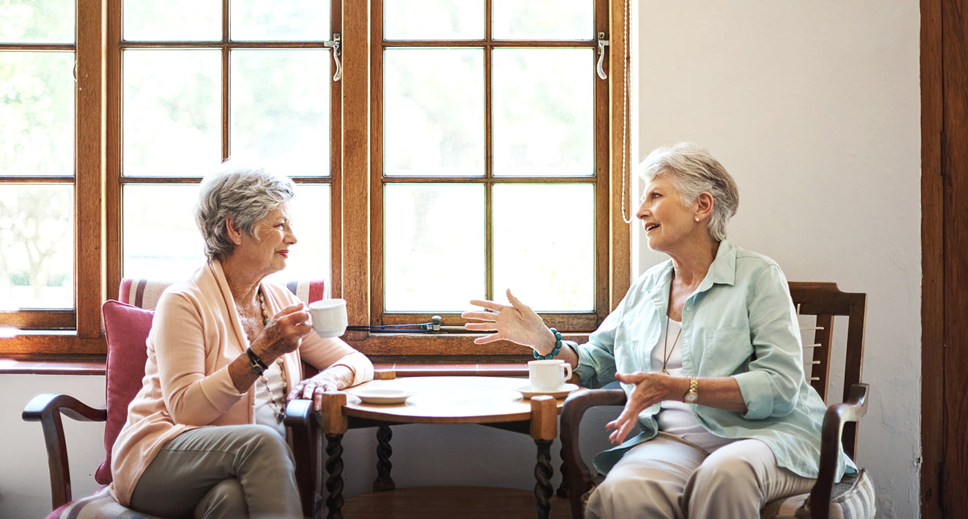 Two older ladies sitting at a coffee table