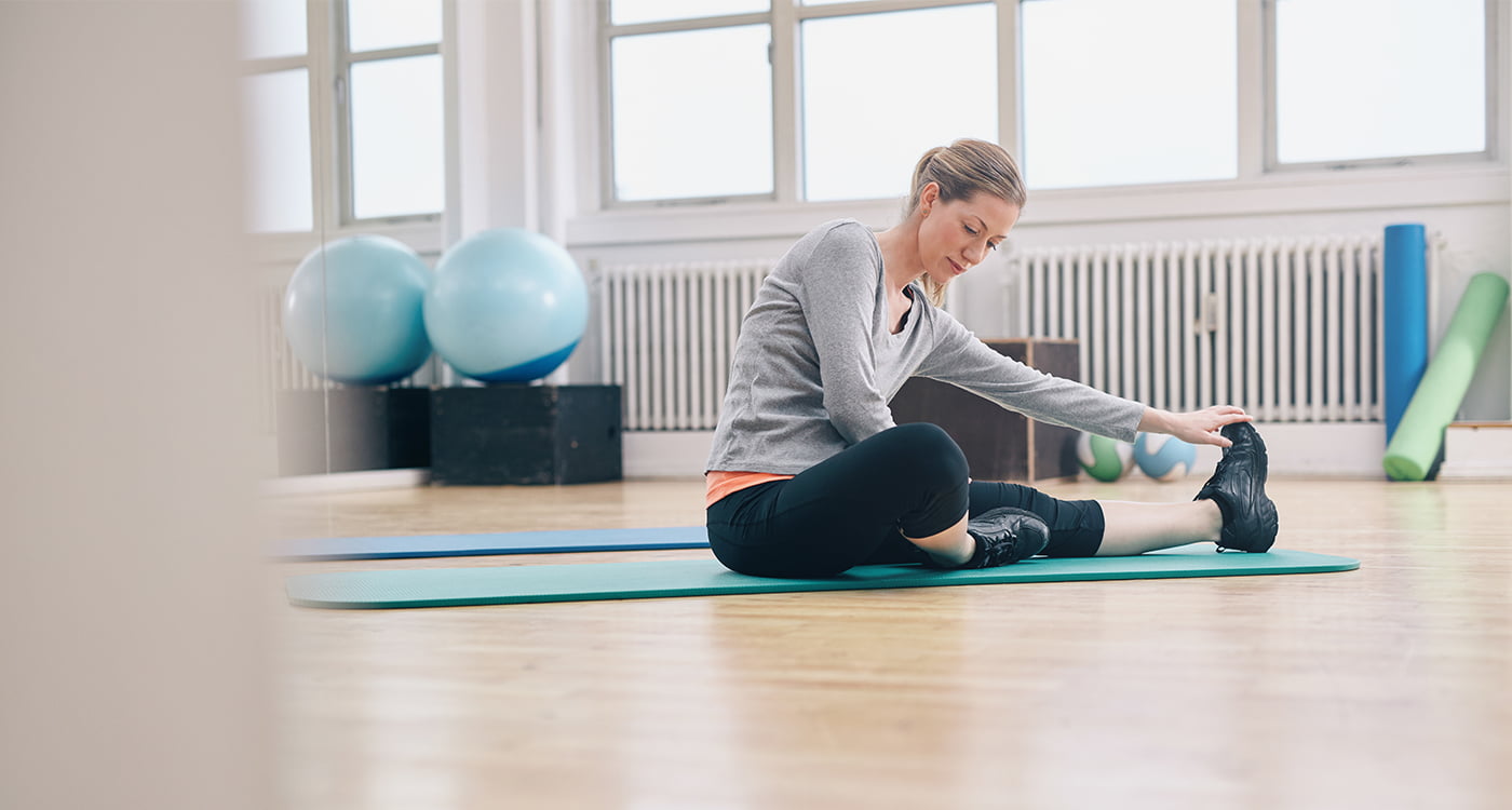 woman sitting on a yoga mat stretching