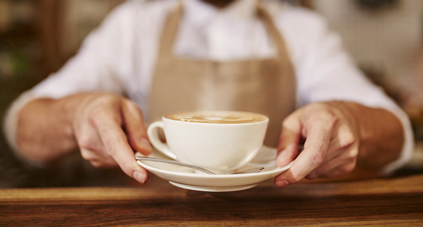 hands holding a coffee cup on a saucer
